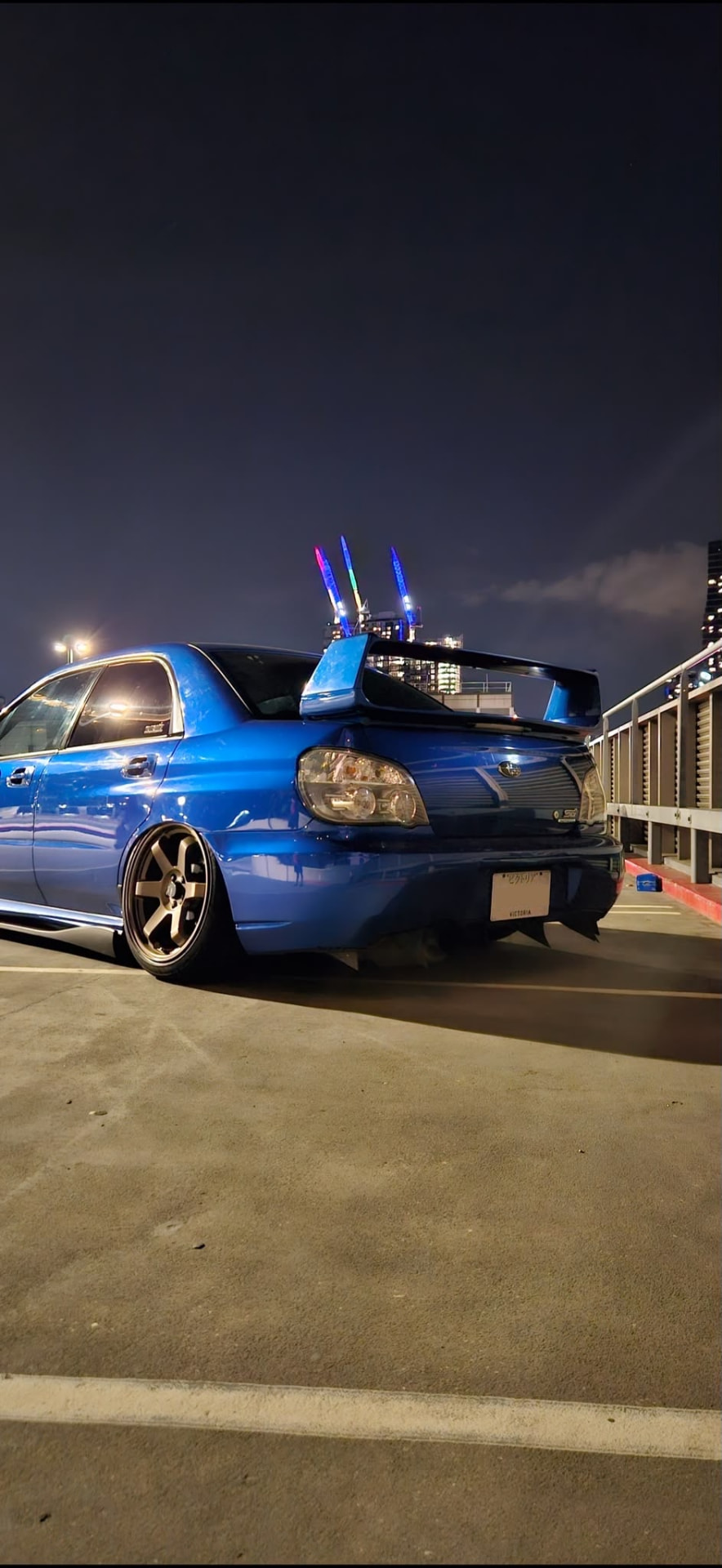 Blue Subaru Impreza sedan on a rooftop car park at night with clear tail lights lit