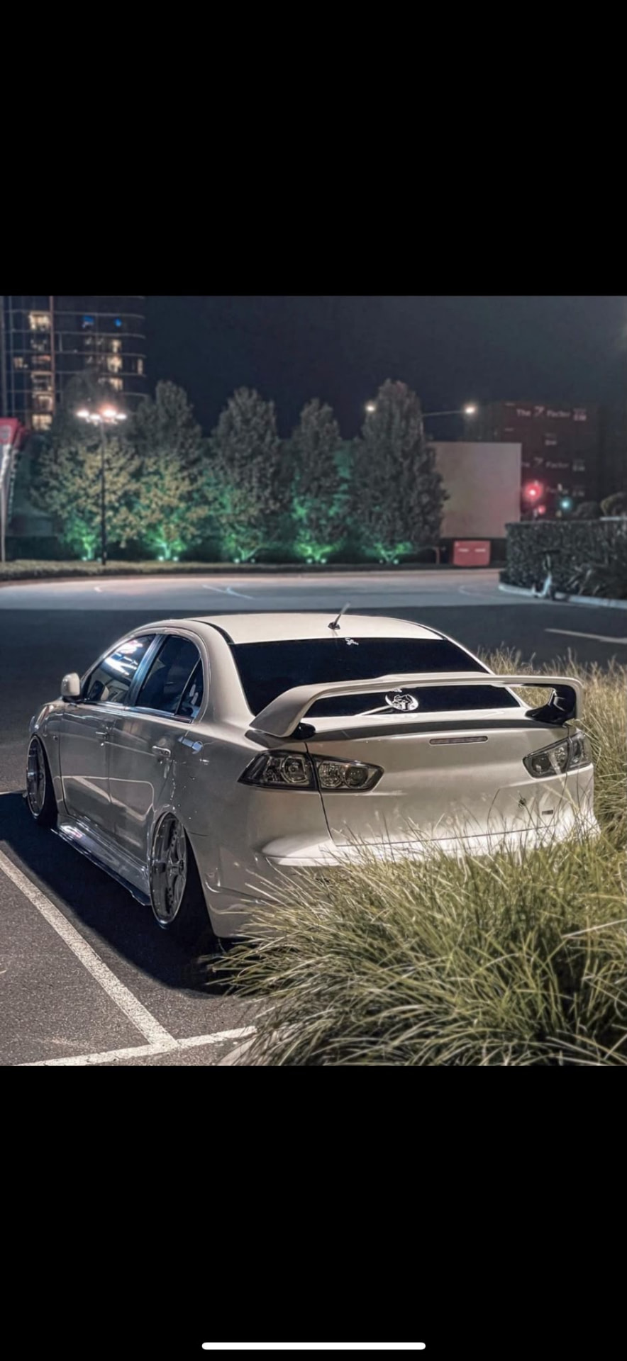 White Mitsubishi Lancer CJ sedan at night in a car park with clear tail lights fitted